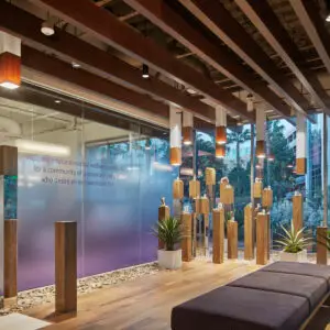 Modern office space with commercial glass films, wooden columns, plants, and soft seating creating a stylish and welcoming environment.