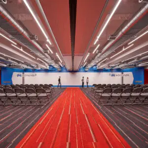 Conference room with rows of chairs, featuring a custom-branded writable wall with the 'edmunds' logo and a person walking by.